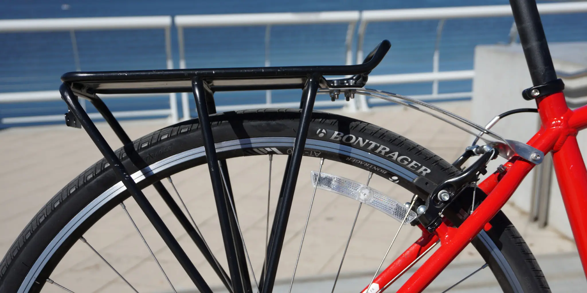 Black bicycle rear rack mounted on a red bike outdoors